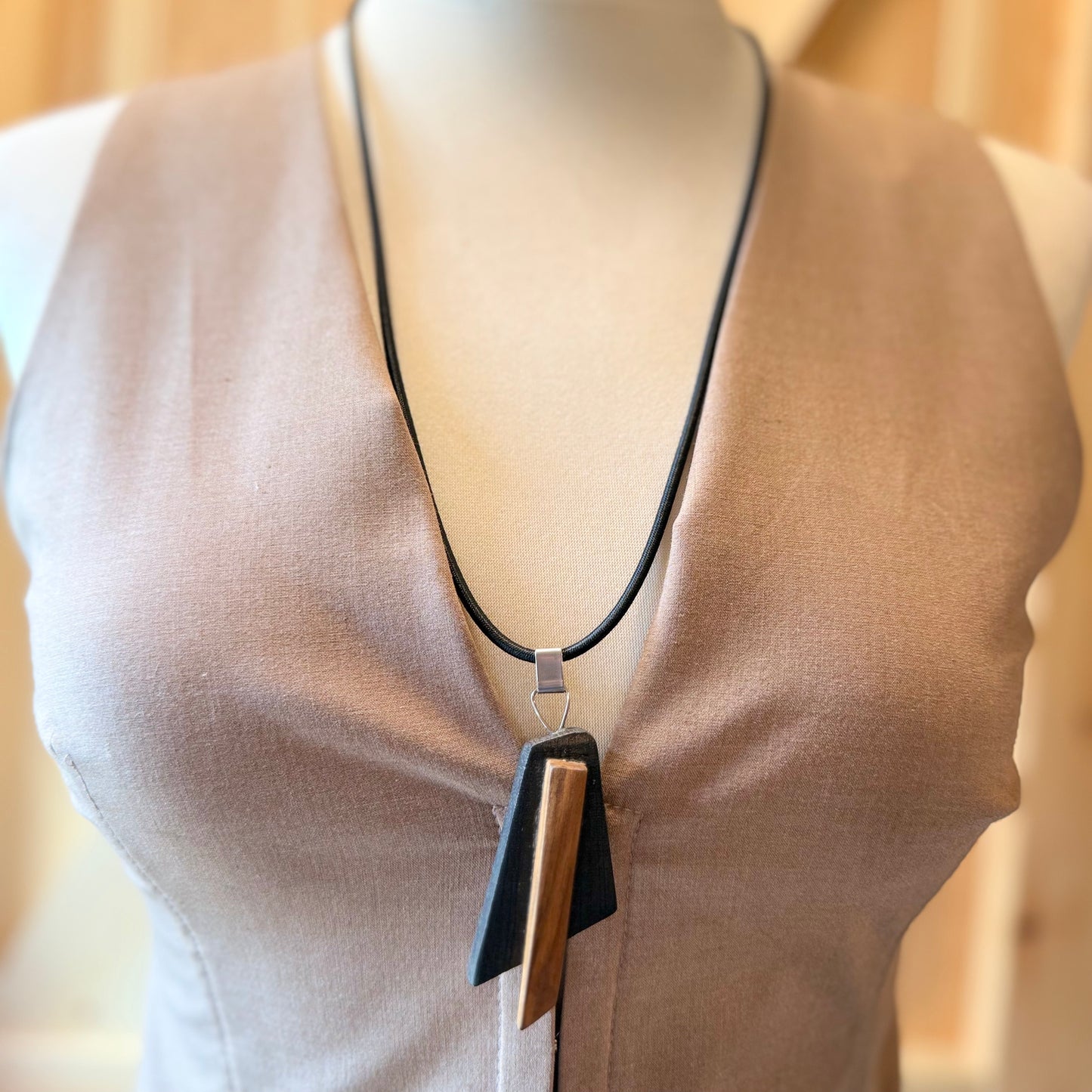 Minimalist geometric wood pendant necklace on black background