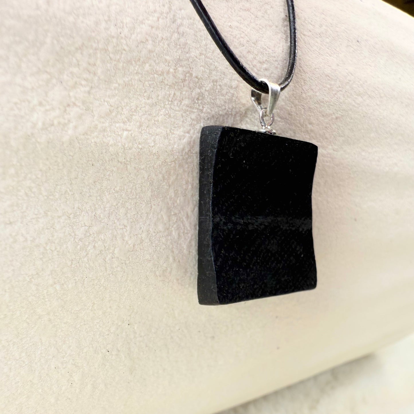Black pendant necklace on a white cushion
