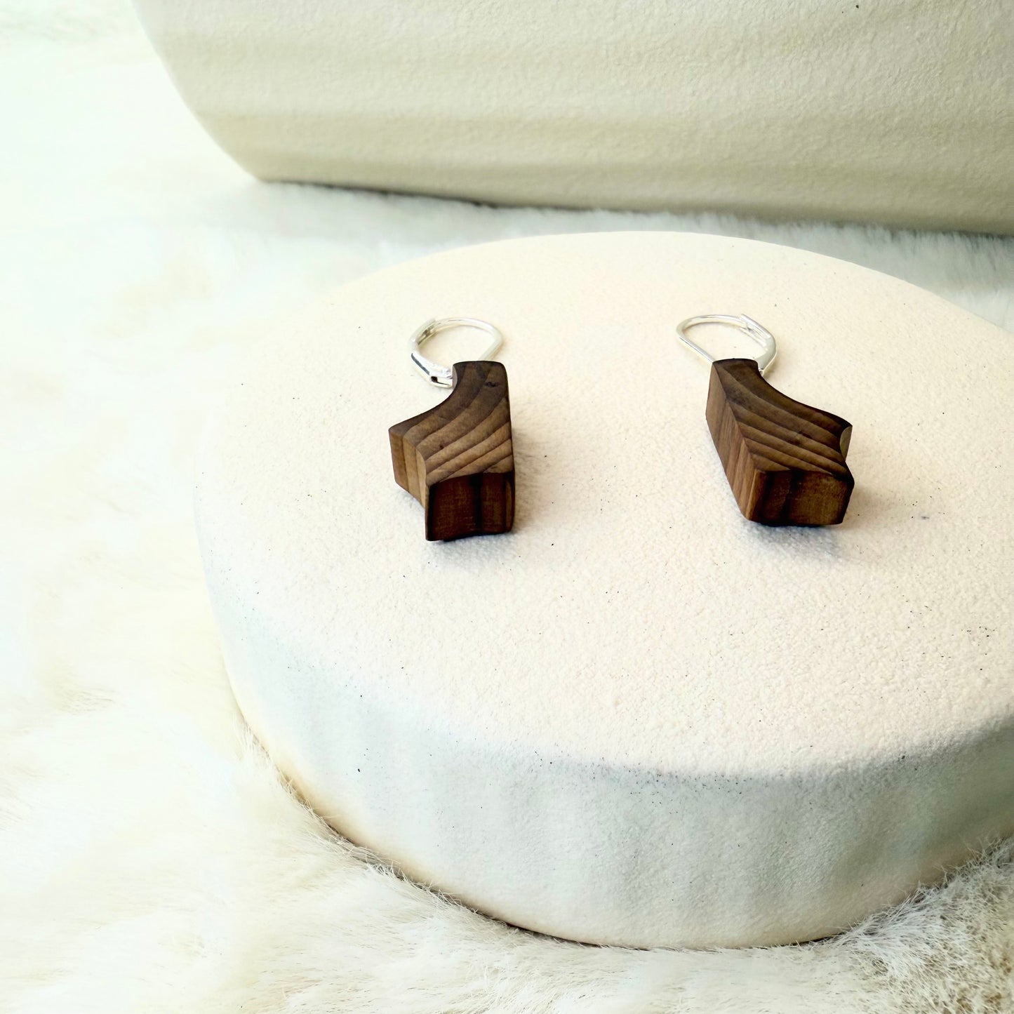Wooden earrings on a white stone surface