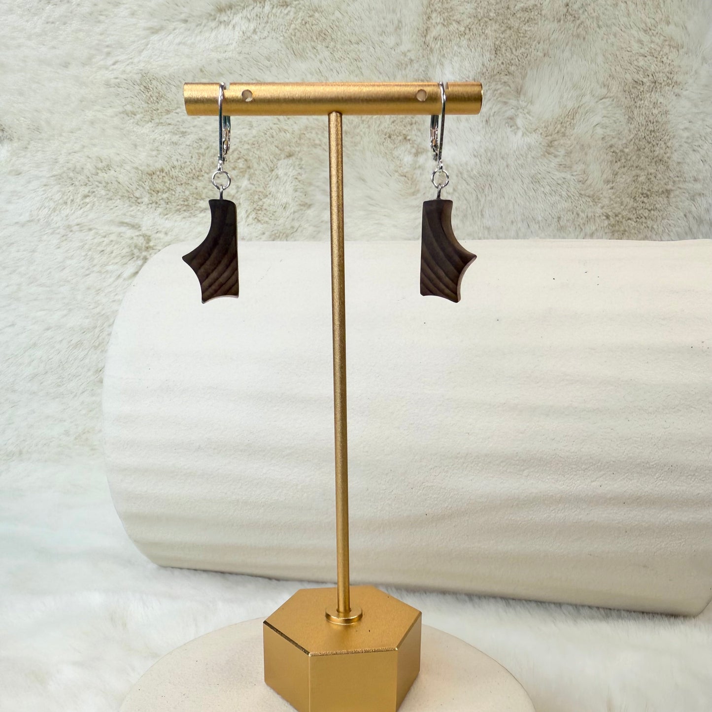 Pair of earrings on a gold stand with a textured background