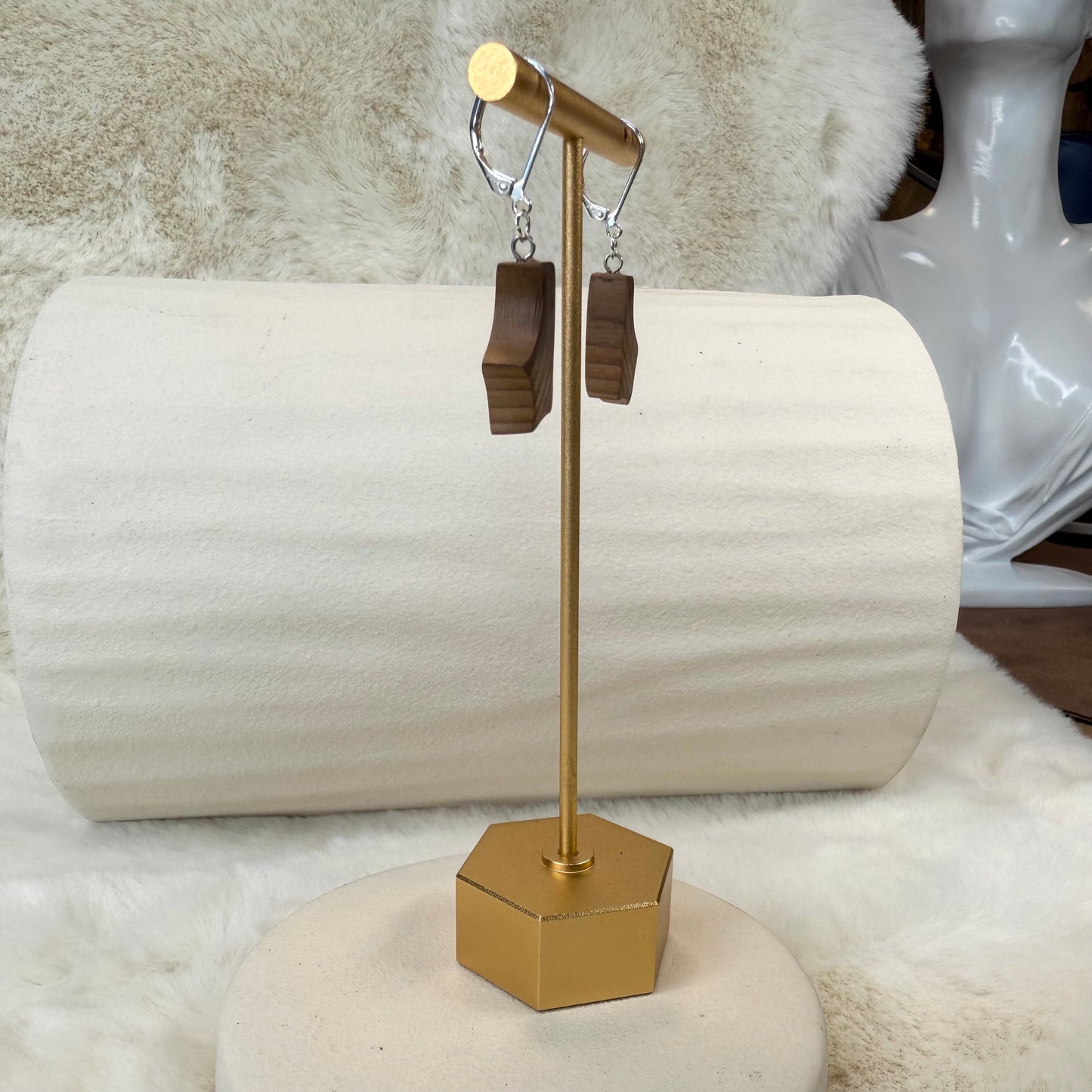 Gold earring stand with wooden earrings on a white surface