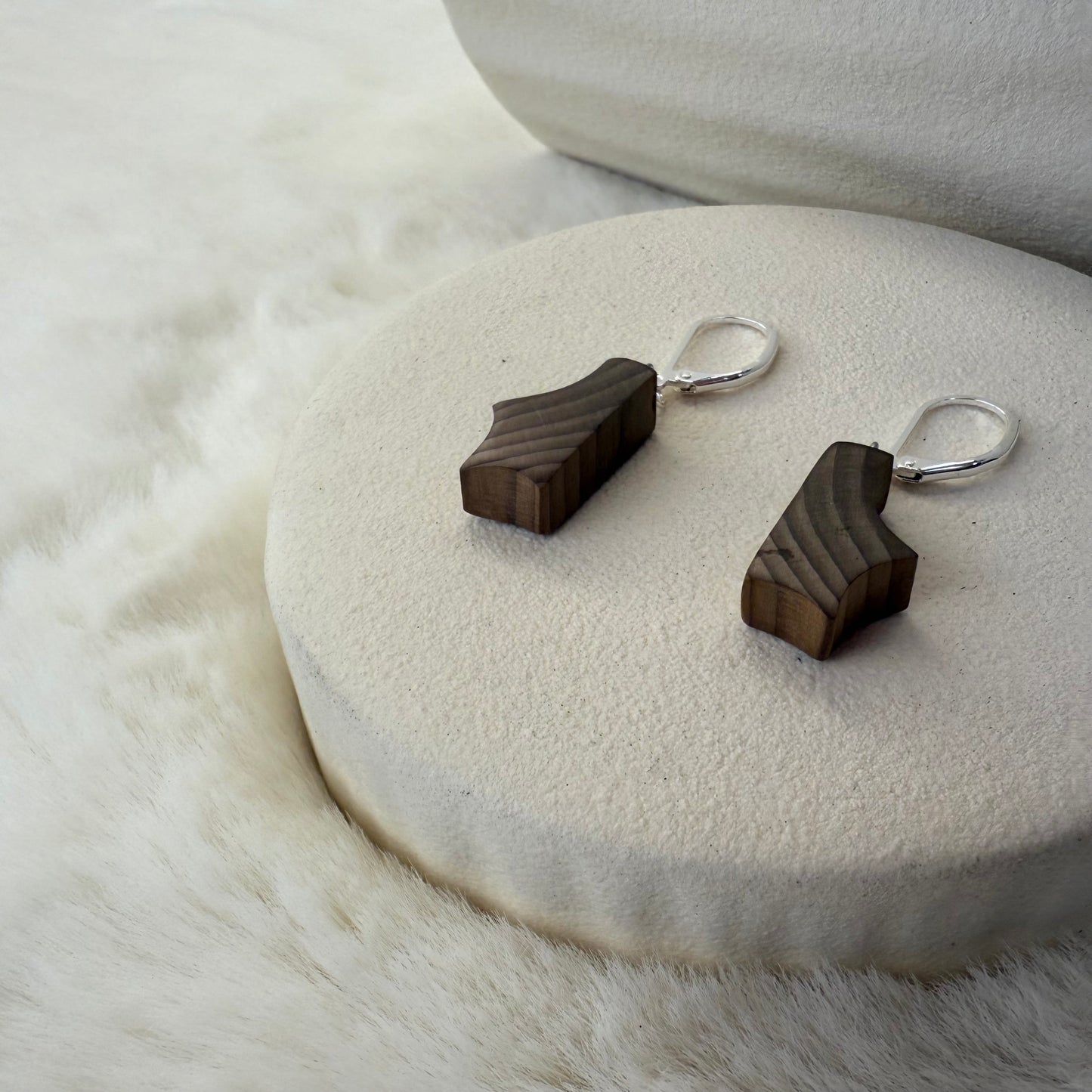 Wooden earrings on a white stone surface