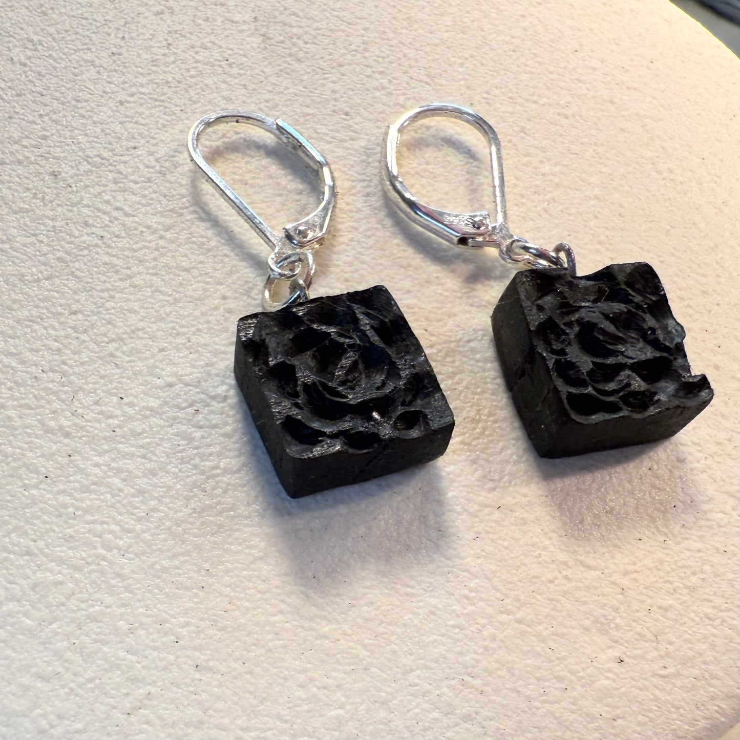 Hand-carved bog oak and sterling silver earrings on white background