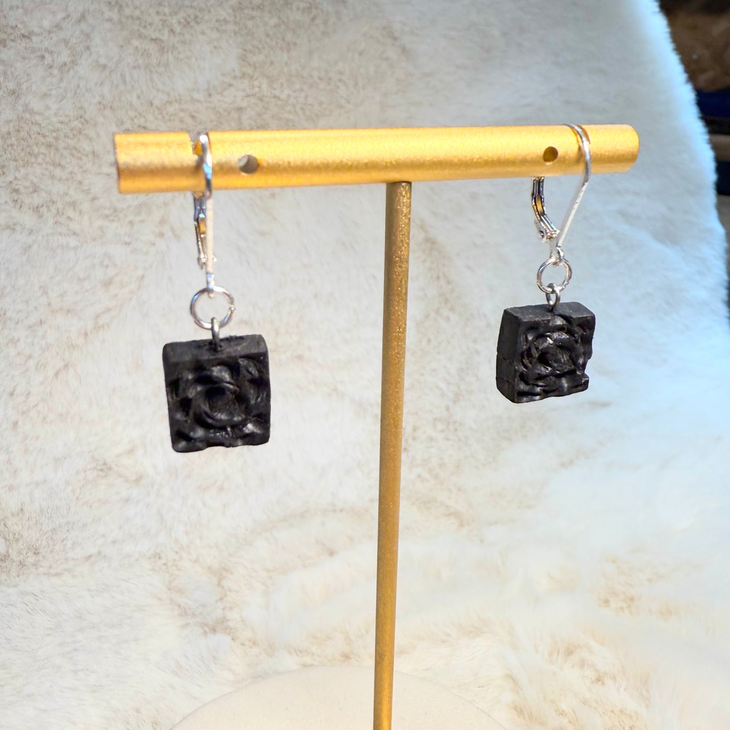 Ancient Irish bog oak earrings hanging on ceramic display stand
