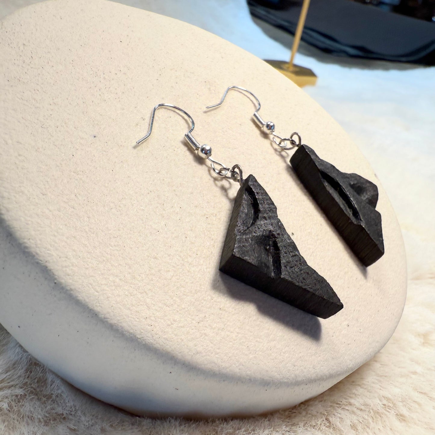 lose-up of bog oak wood texture and geometric triangle shape of handmade earrings.