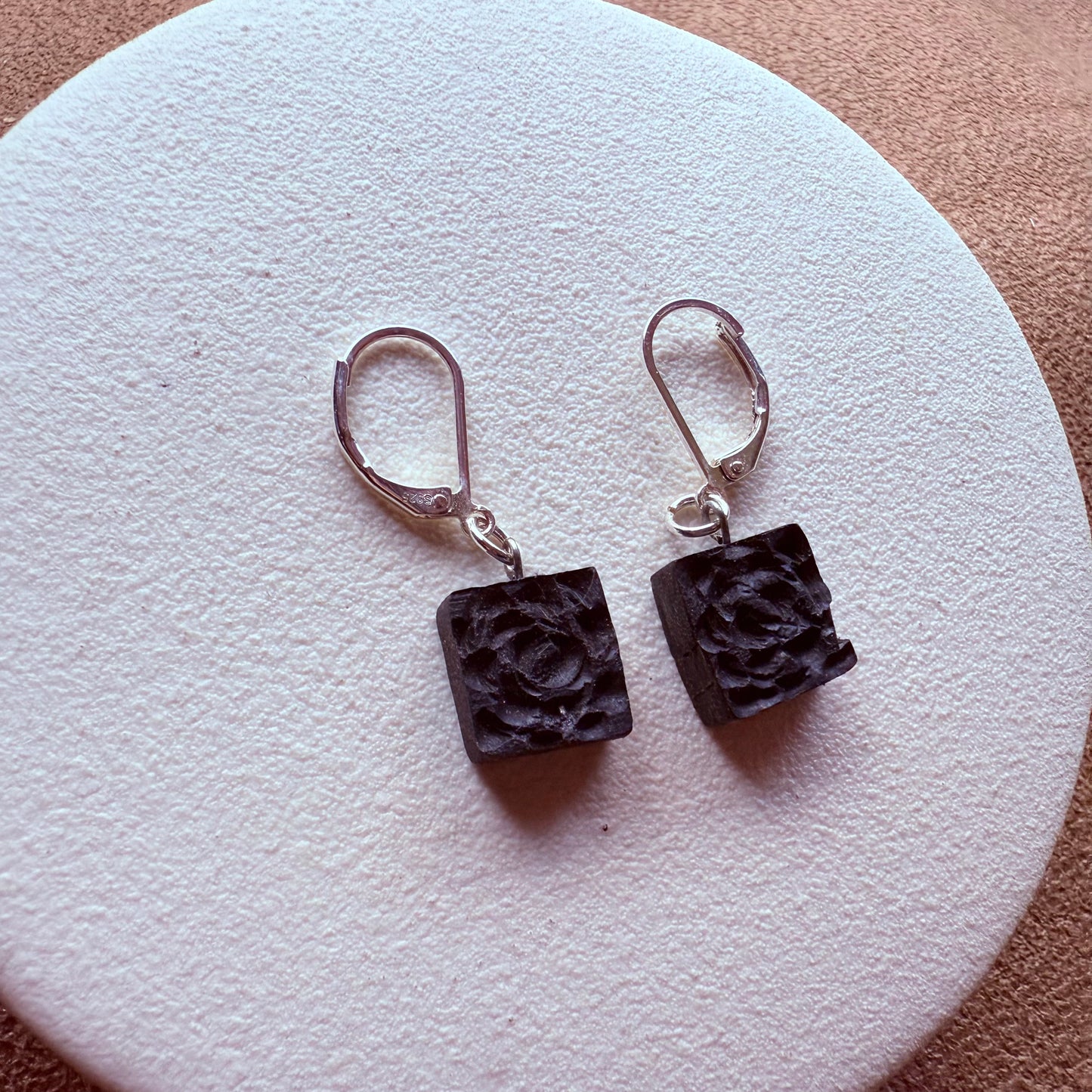 Side view of lightweight wood and silver earrings on display