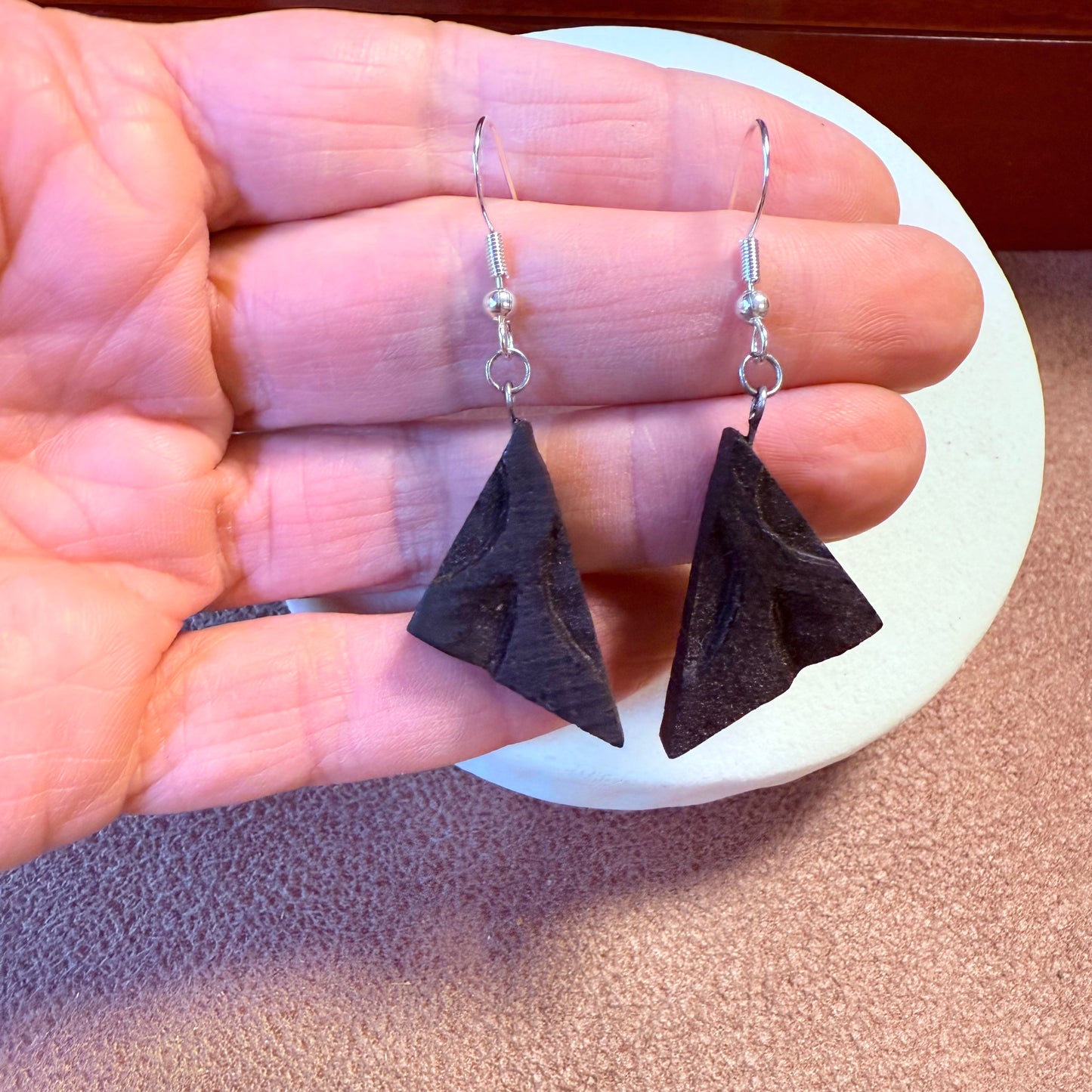 Triangle earrings worn on ear, showing lightweight design.