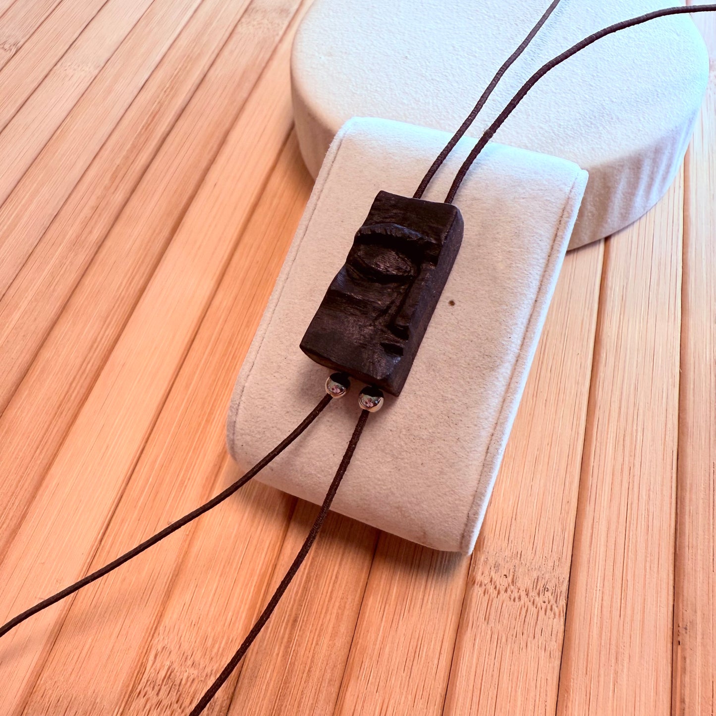 Detail shot of lightweight, handcrafted bog oak face pendant on elastic cord with bead accents.