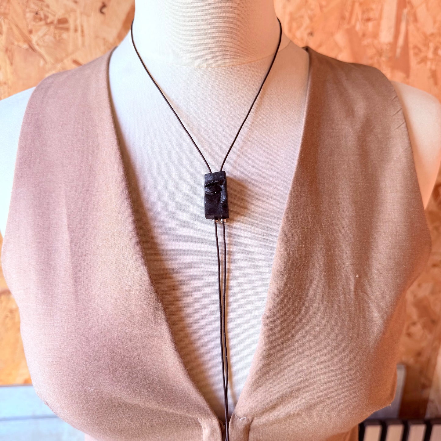 Side view of carved bog oak pendant necklace highlighting craftsmanship and wood grain