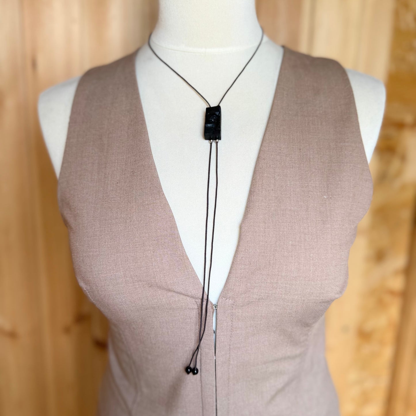 Symbolic face pendant made from thousand-year-old oak wood, shown with minimalistic styling