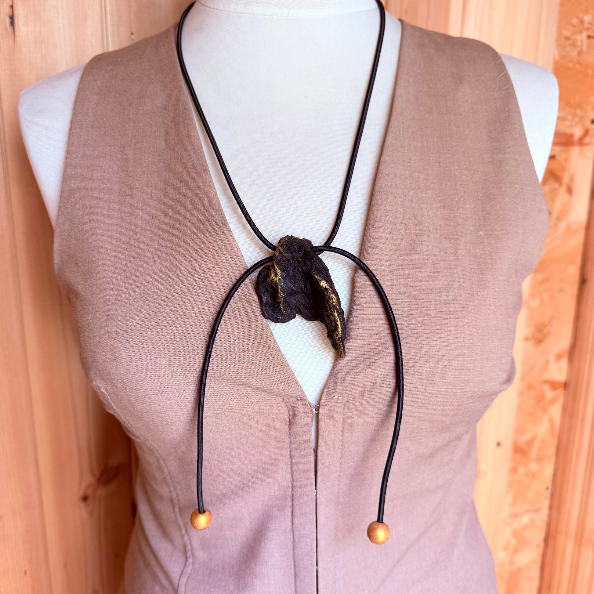 Close-up of black bog oak pendant on minimalist elastic necklace