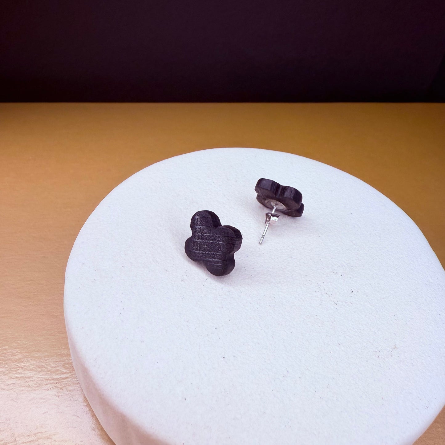 Close-up of handcrafted dark wood clover-shaped stud earrings made from ancient bog oak