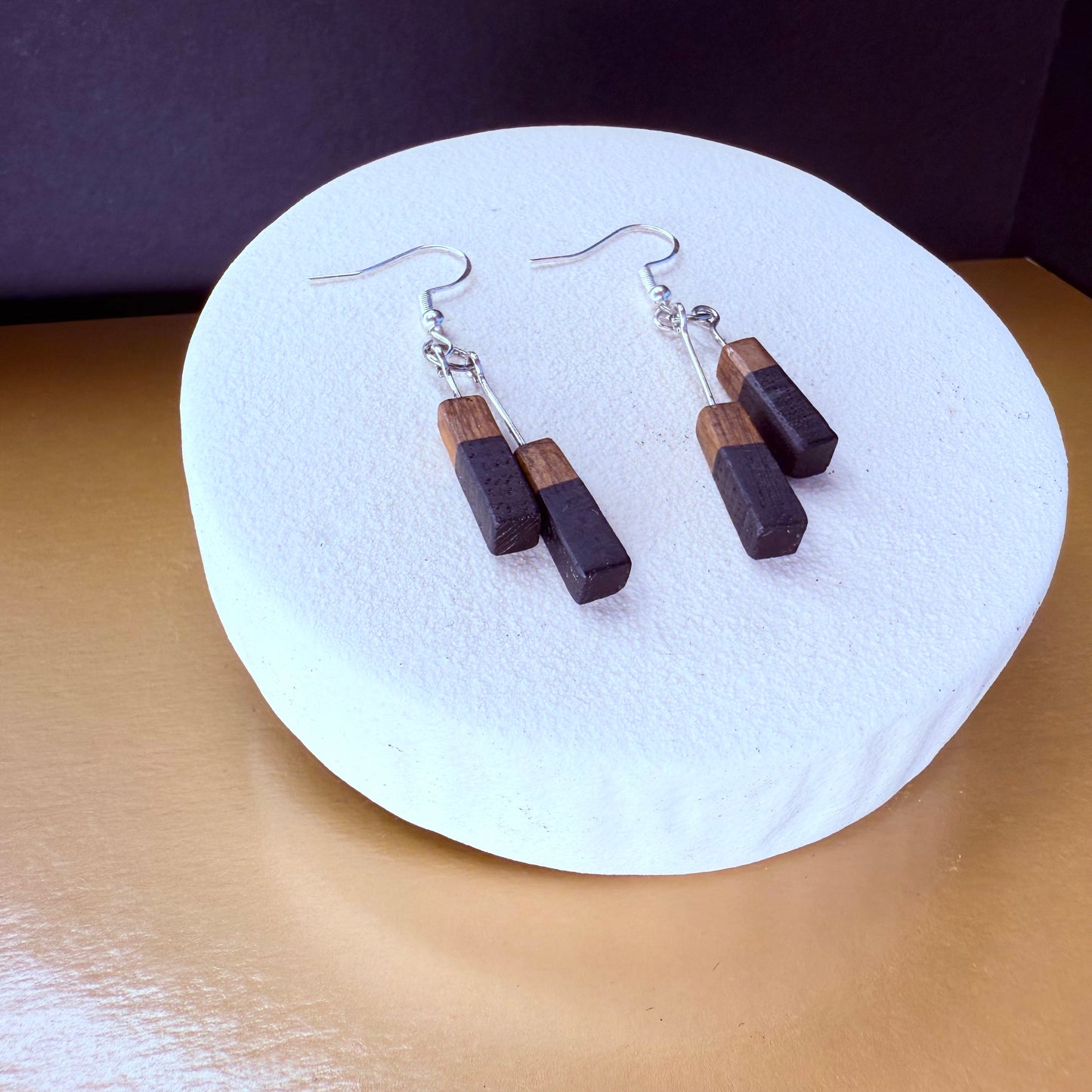 Wooden earrings on a white round stand with a dark background