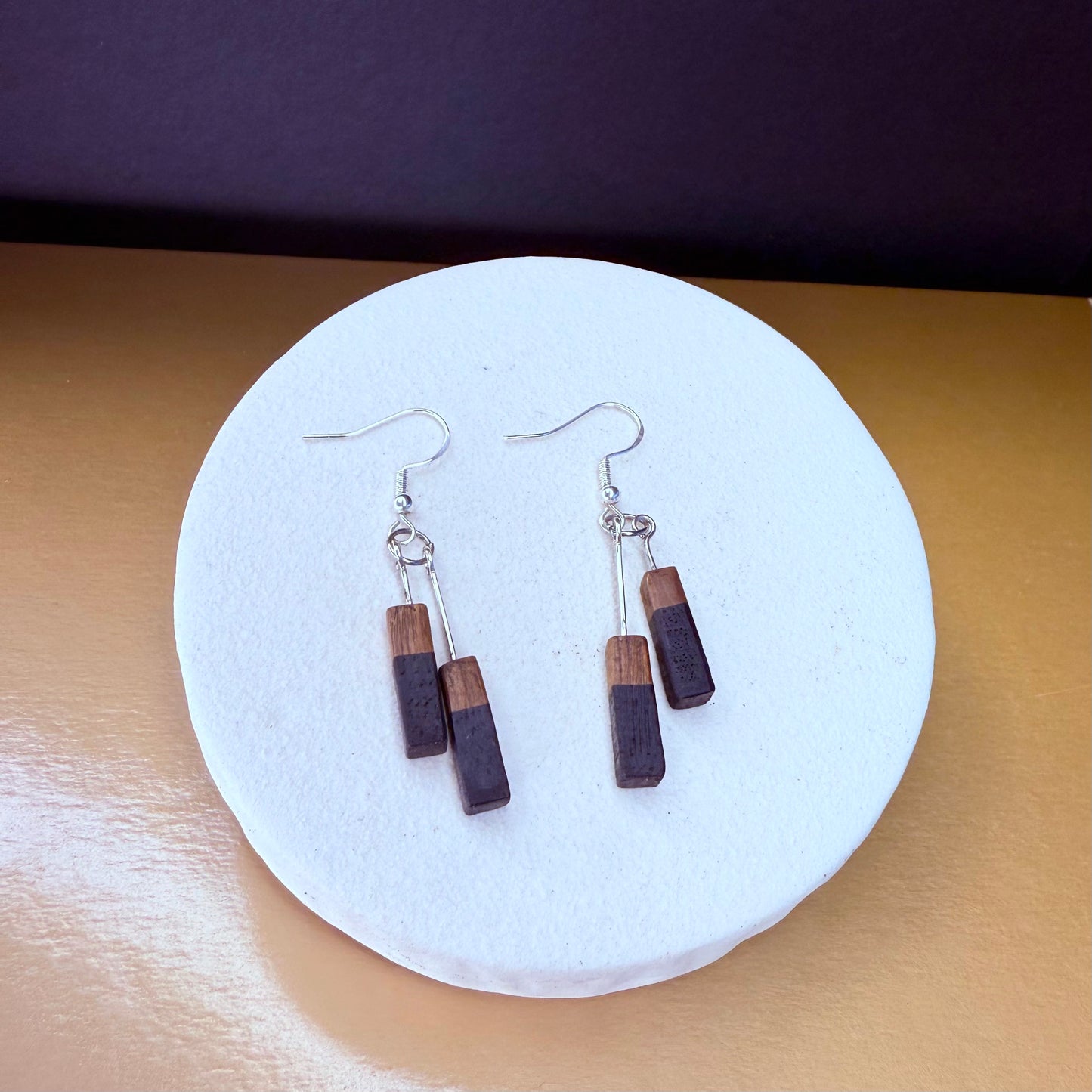 Wooden earrings on a white circular stand with a purple background