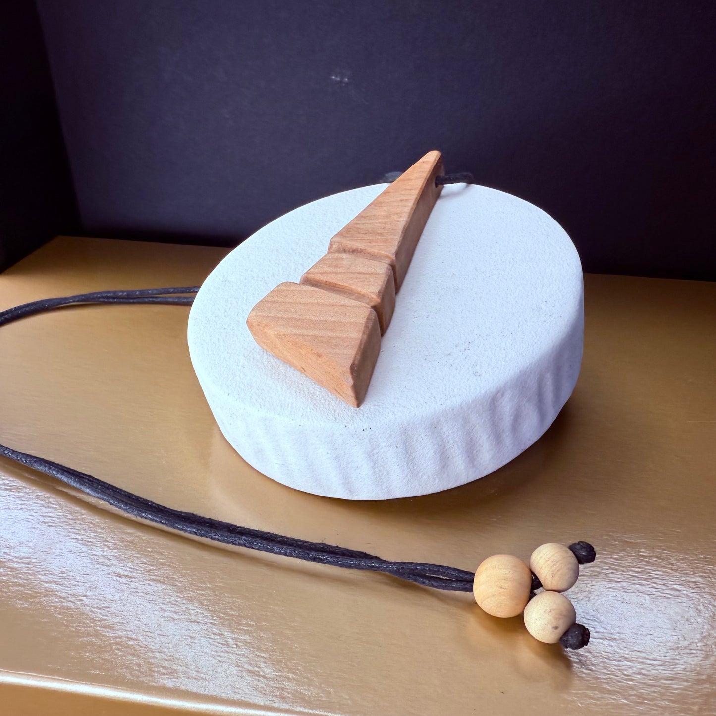 Handcrafted apple wood pendant necklace shown from side, highlighting unique natural wood grain