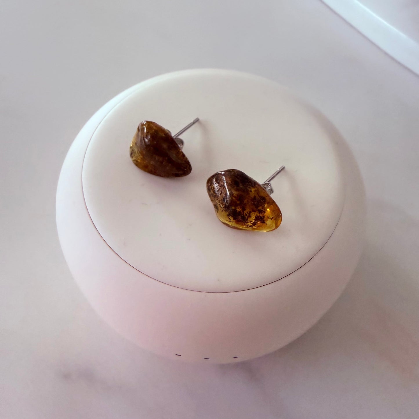 Amber-colored earrings on a white round container