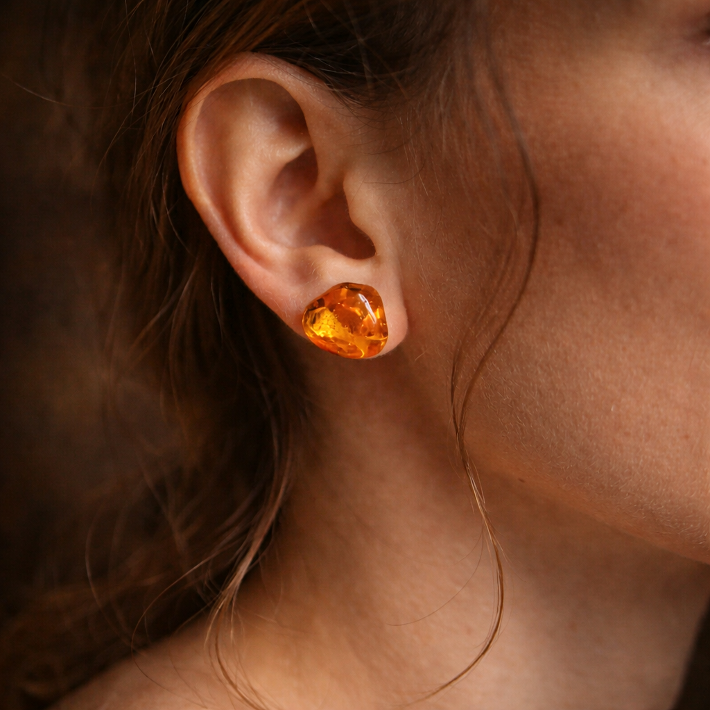 Close-up of an ear wearing a heart-shaped amber earring.