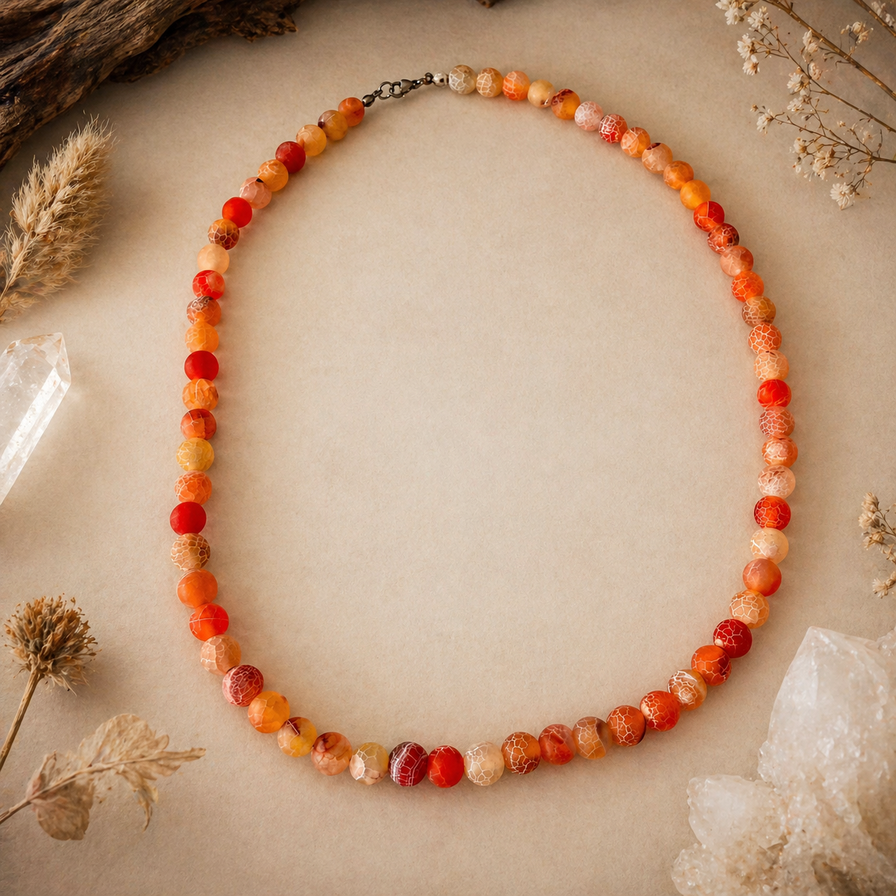 Necklace with multicolored beads on a neutral background with dried plants and crystals.