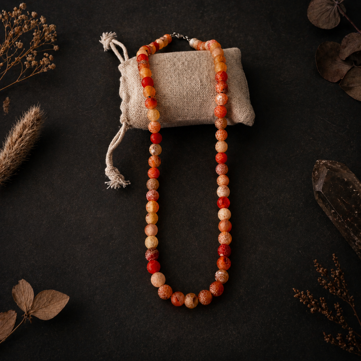 Beaded necklace on a dark surface with dried plants