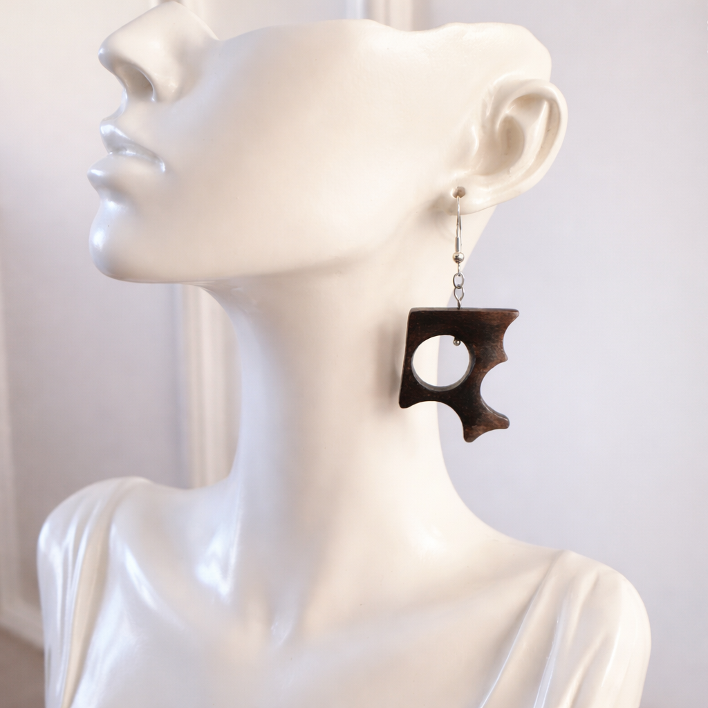 Wooden earring on a mannequin ear against a white background