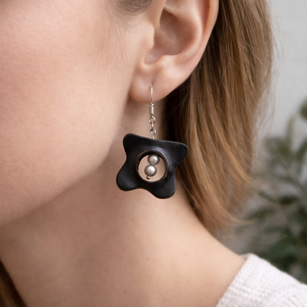 Close-up of a person wearing a black earrings with a pearl detail.