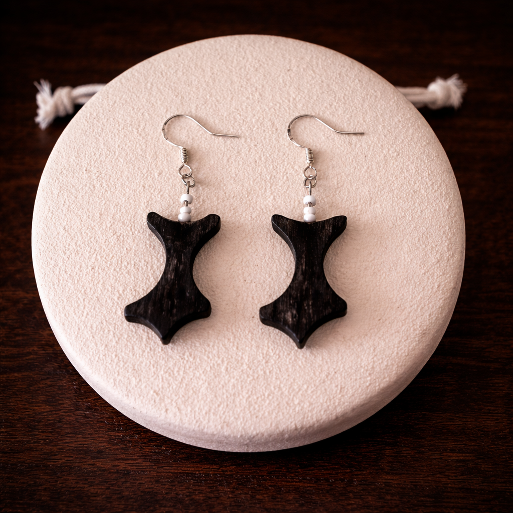 Black earrings on a white stone with a dark wooden background