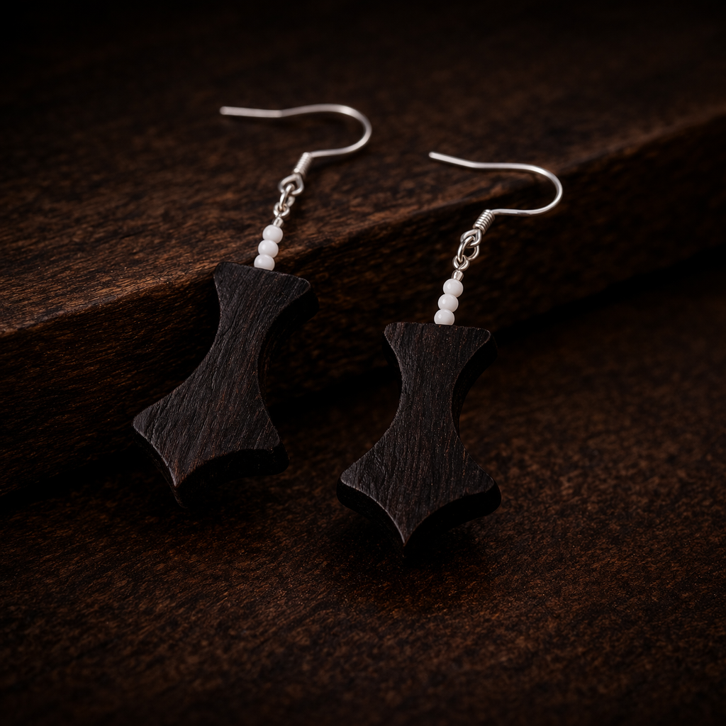 Black earrings with white beads on a dark brown surface