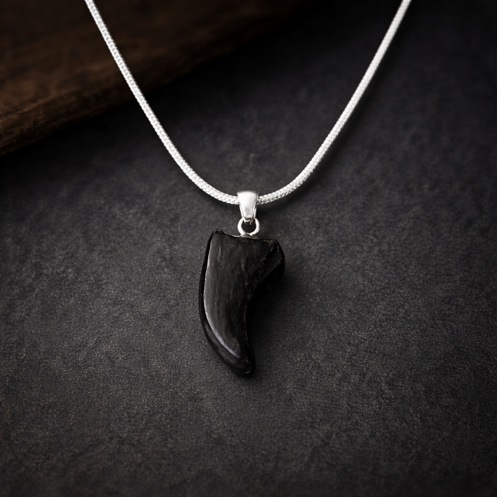 Black pendant on a silver chain against a dark background
