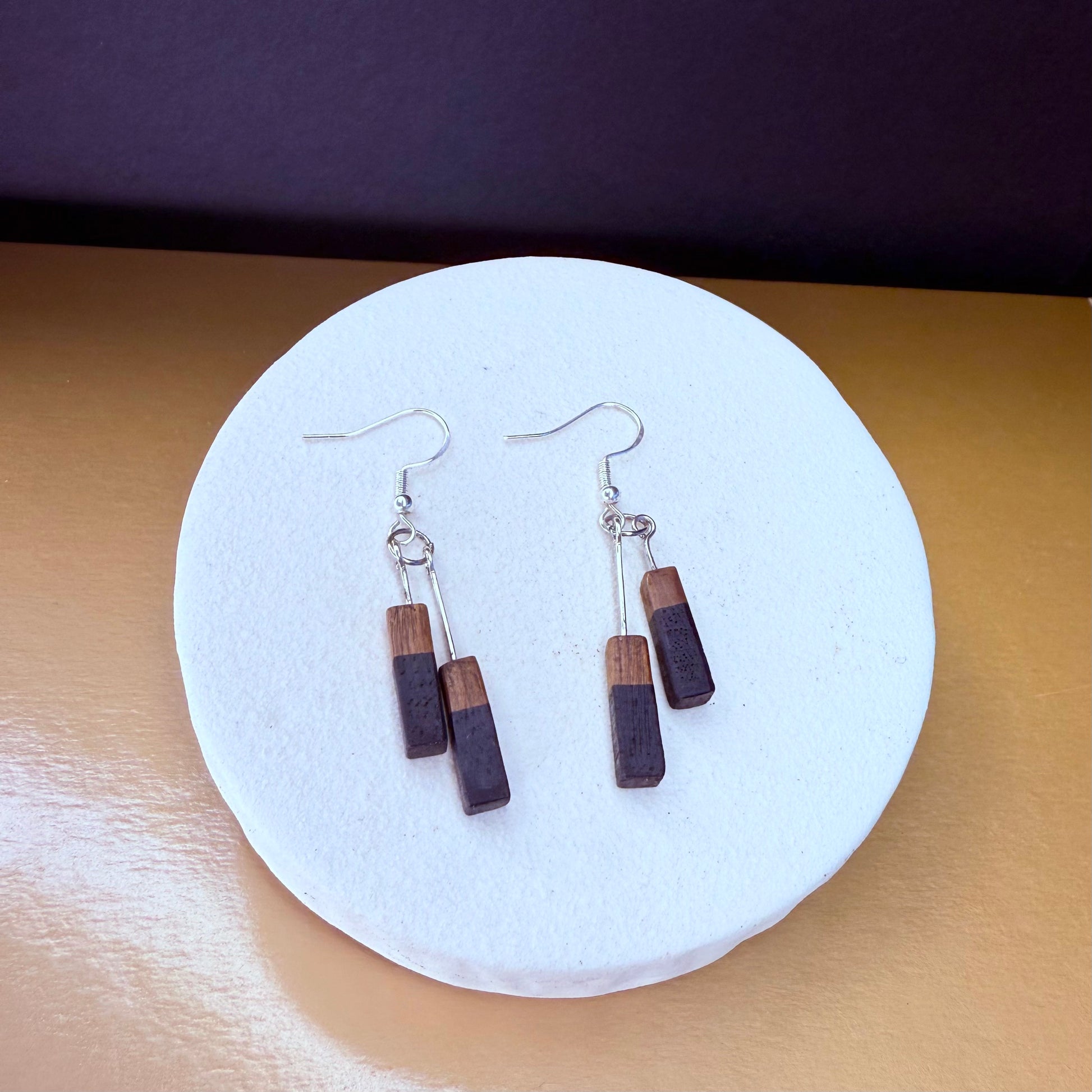 Wooden earrings on a white circular stand with a purple background