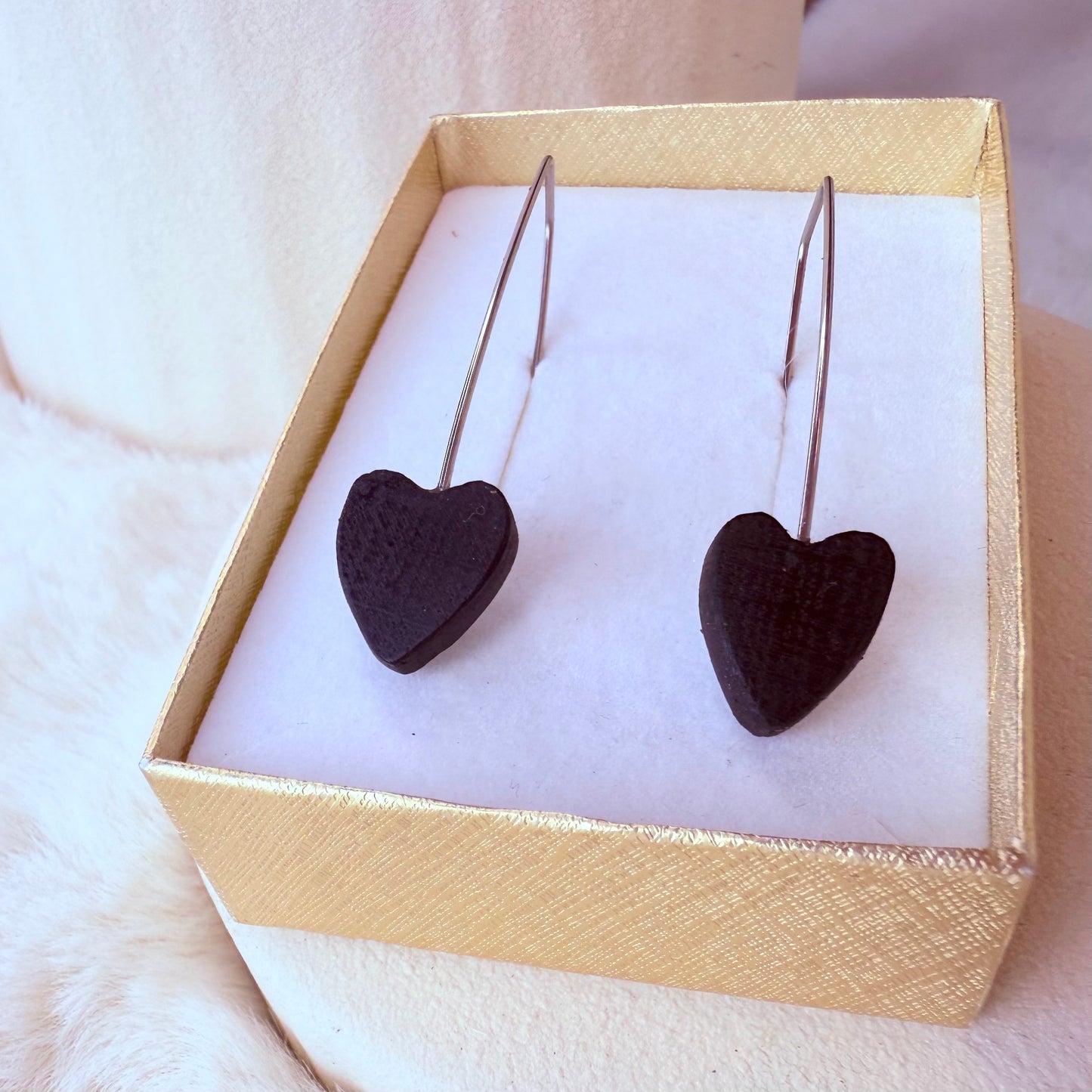 Heart-shaped earrings in a gold box on a white surface