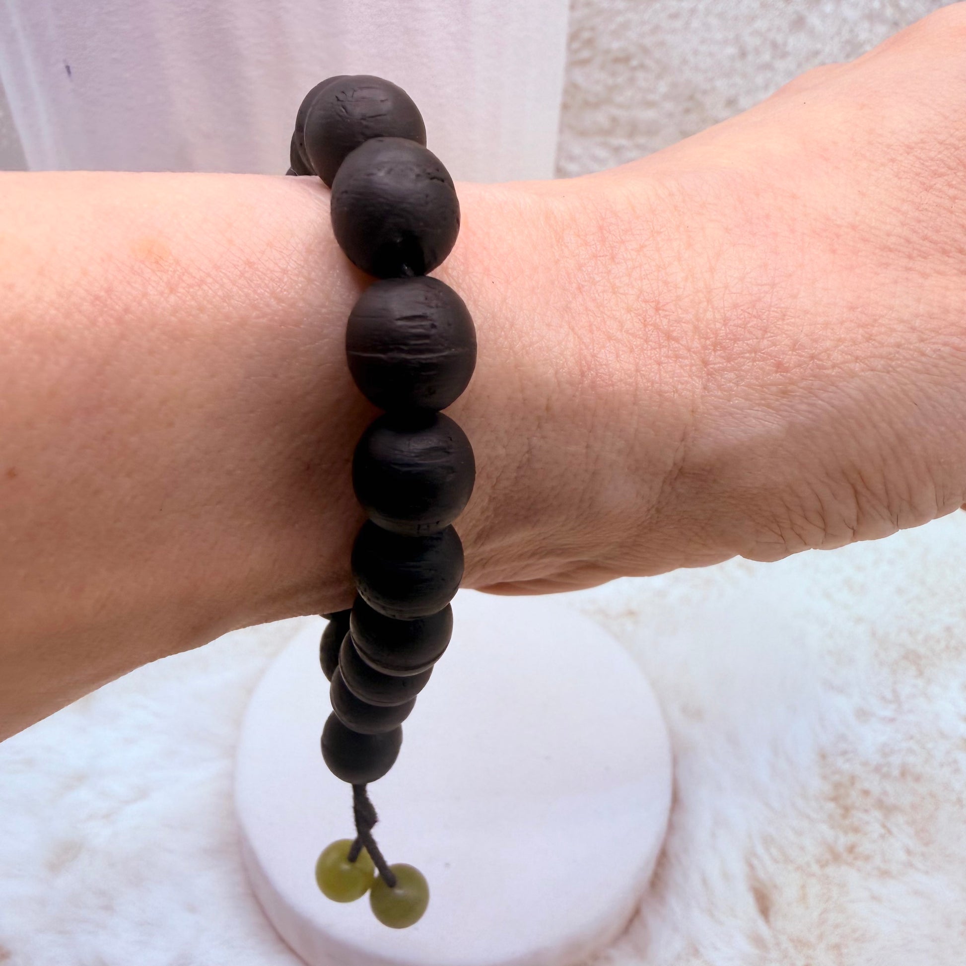 Black beaded bracelet on a wrist with a white background