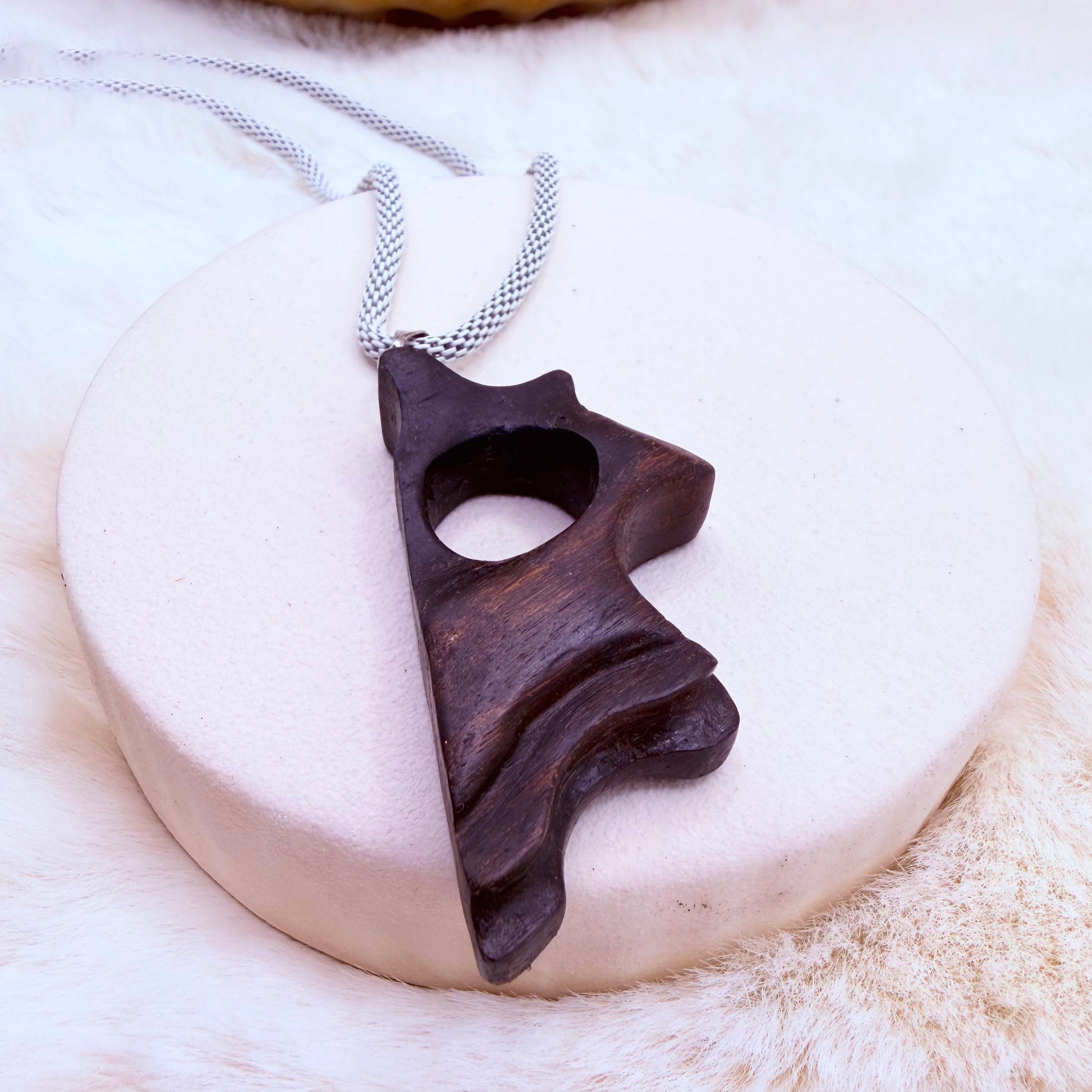 Close-up of ancient bog oak pendant showing dark wood grain and organic shape.