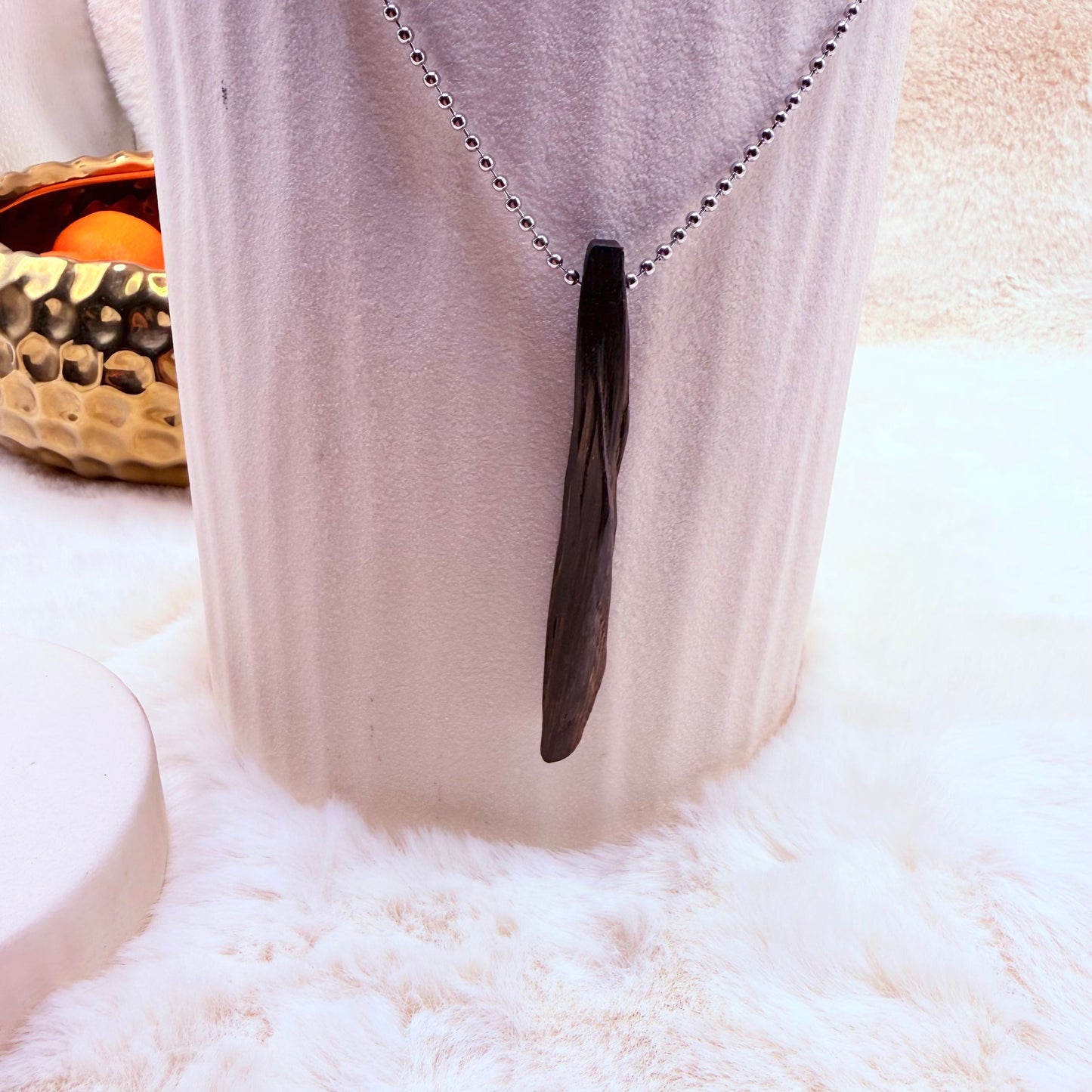 Black pendant necklace on a chain against a white background