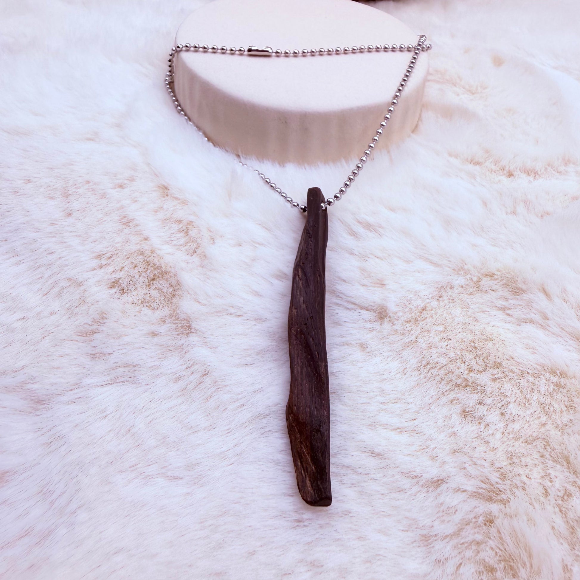 Driftwood pendant necklace on a white fur surface