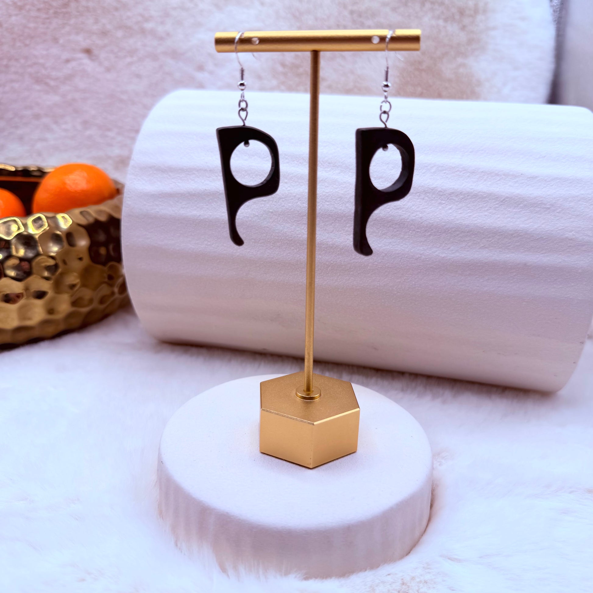 Black 'P' shaped earrings on a gold stand 