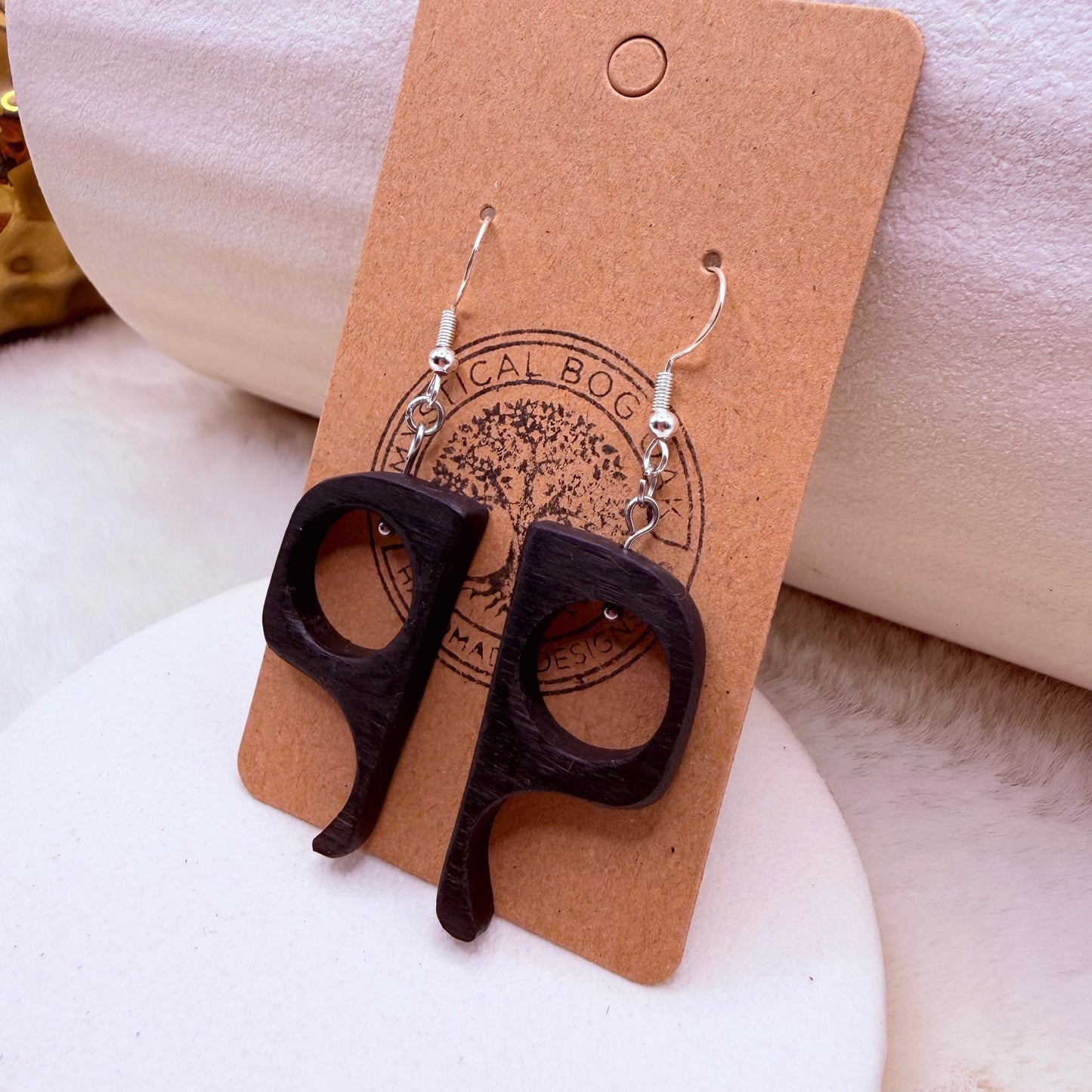 Hand-carved bog oak dangle earrings shown on a neutral background, elongated organic shape visible.