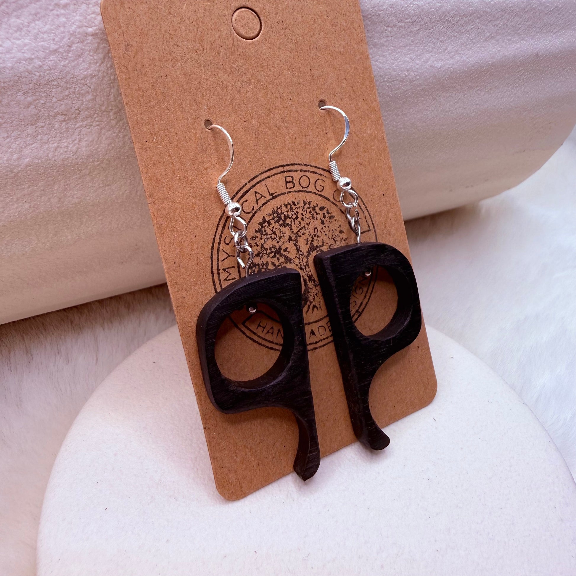 Close-up of bog oak earrings highlighting natural wood grain and smooth dark finish.