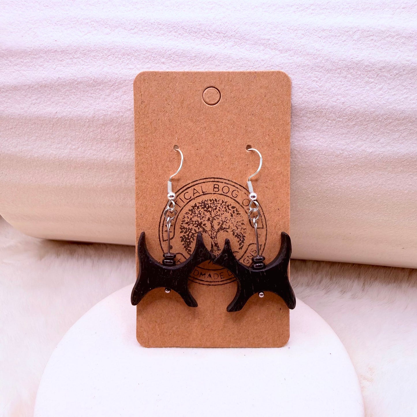 Black bog oak cat-shaped dangle earring with hematite bead on mannequin display.