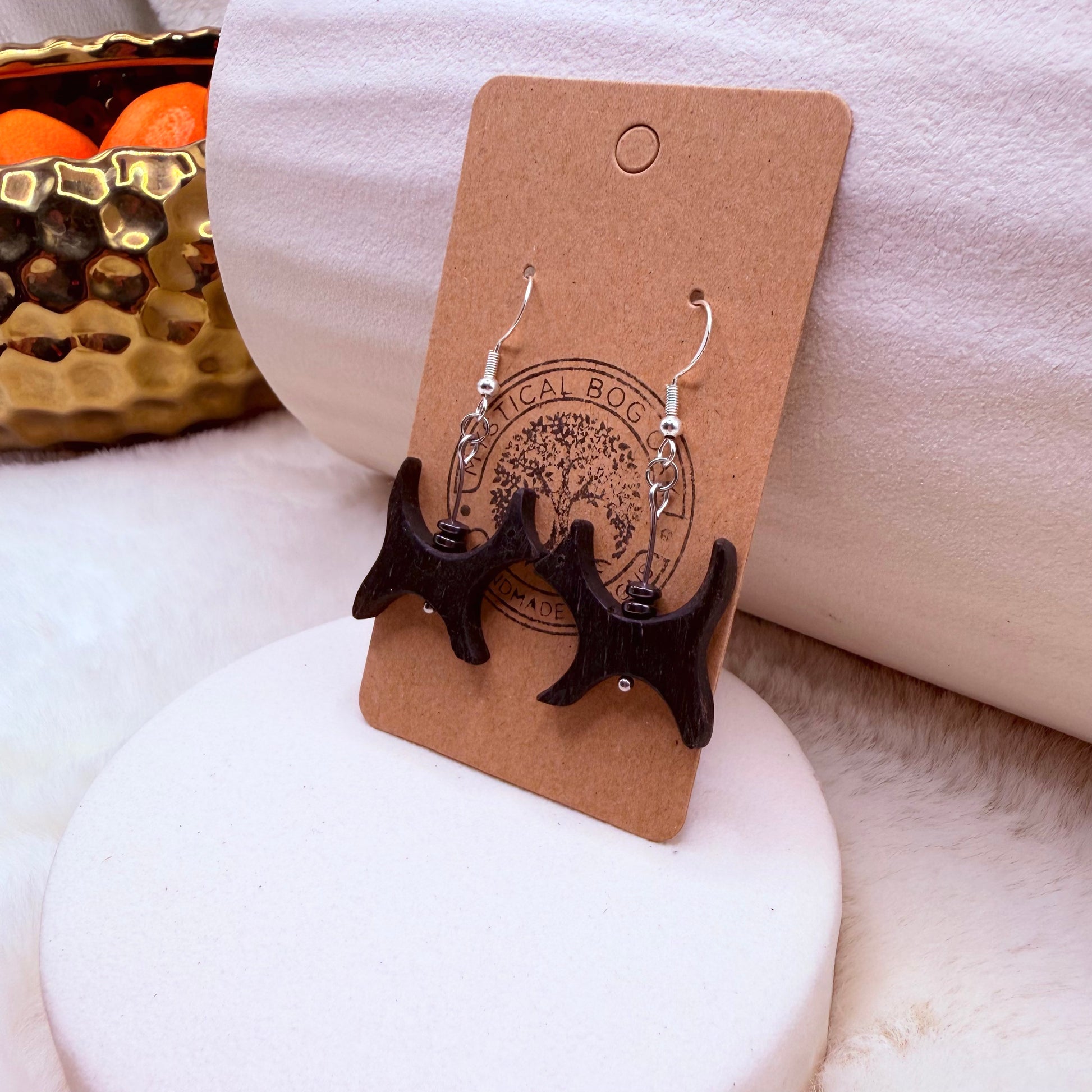 Close-up of dark wooden cat silhouette earring with small hematite accents.