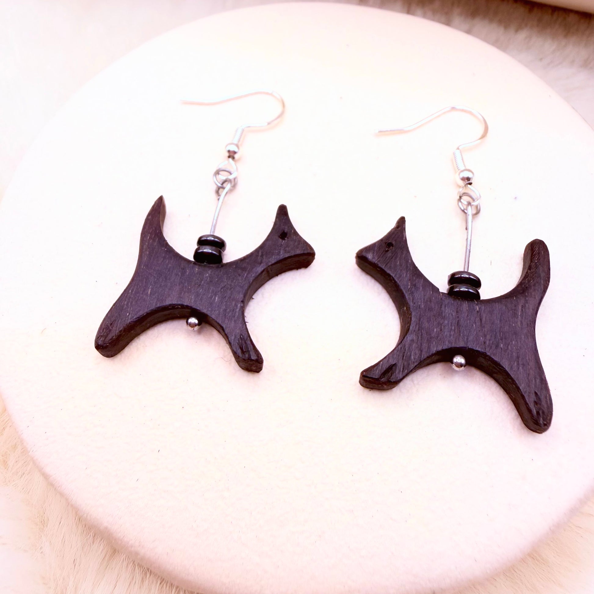 Wooden earrings with black accents on a white plate