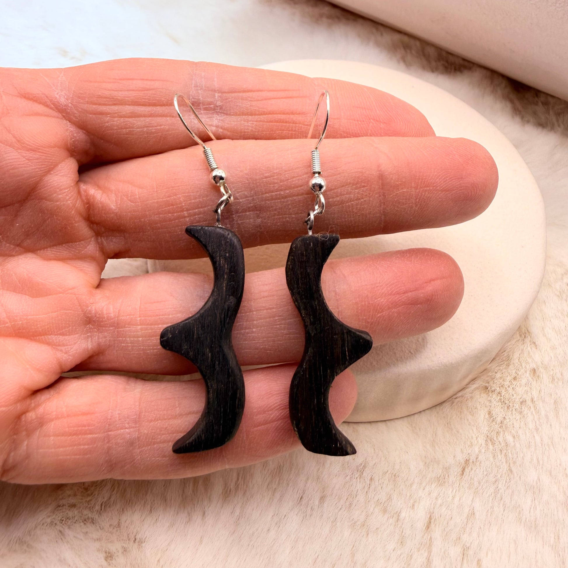 Hand-carved bog oak wood earrings hanging on silver-tone hooks