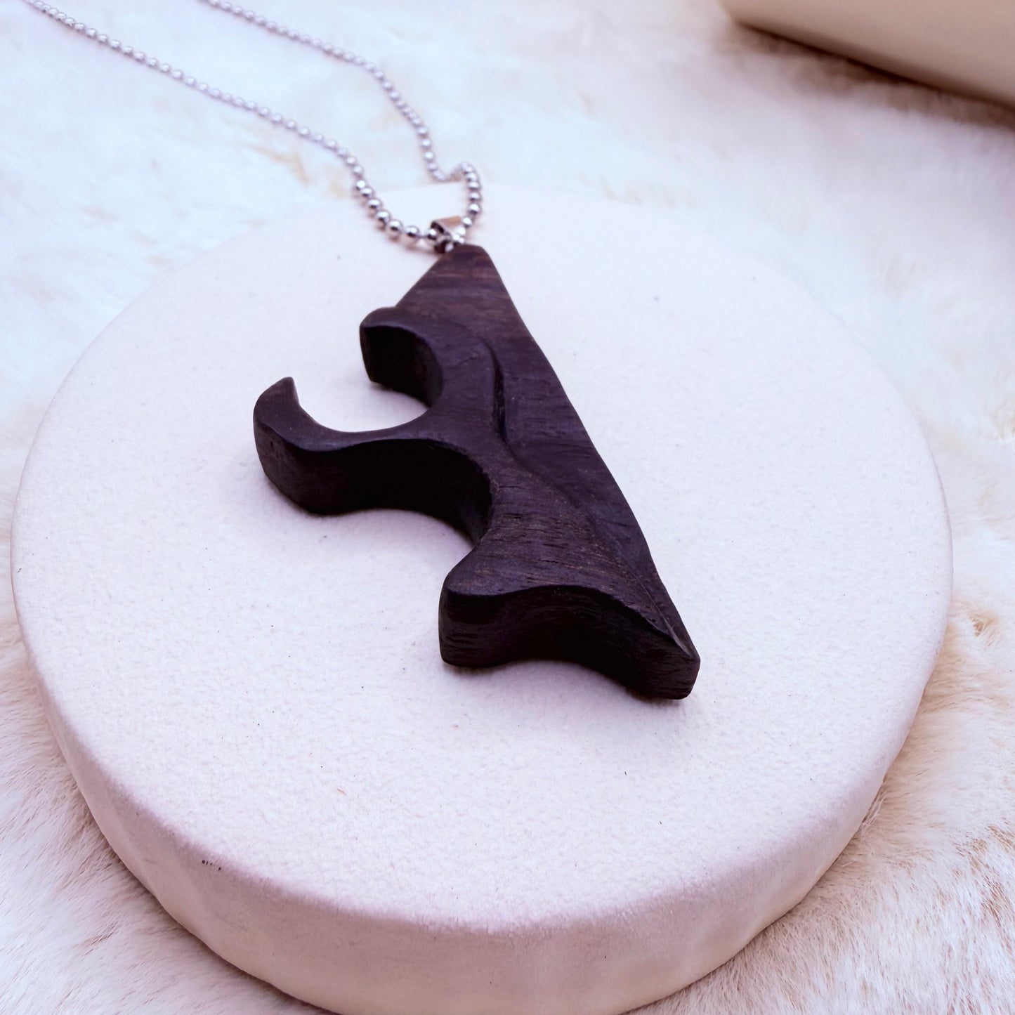 Wooden pendant necklace on a white stone surface