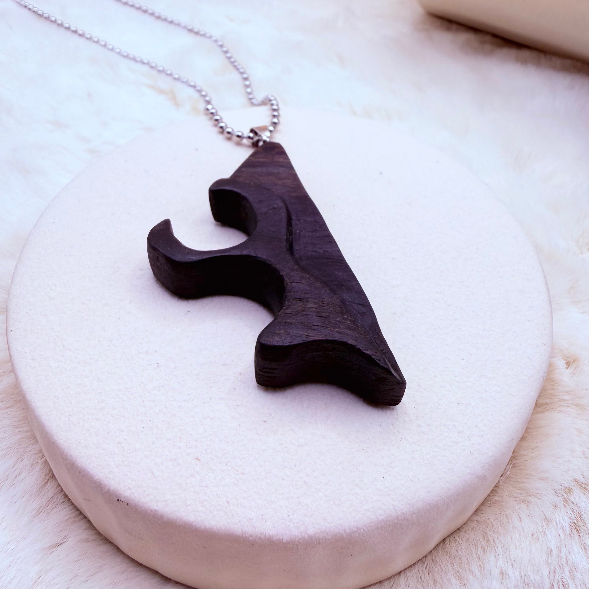 Wooden pendant necklace on a white stone surface