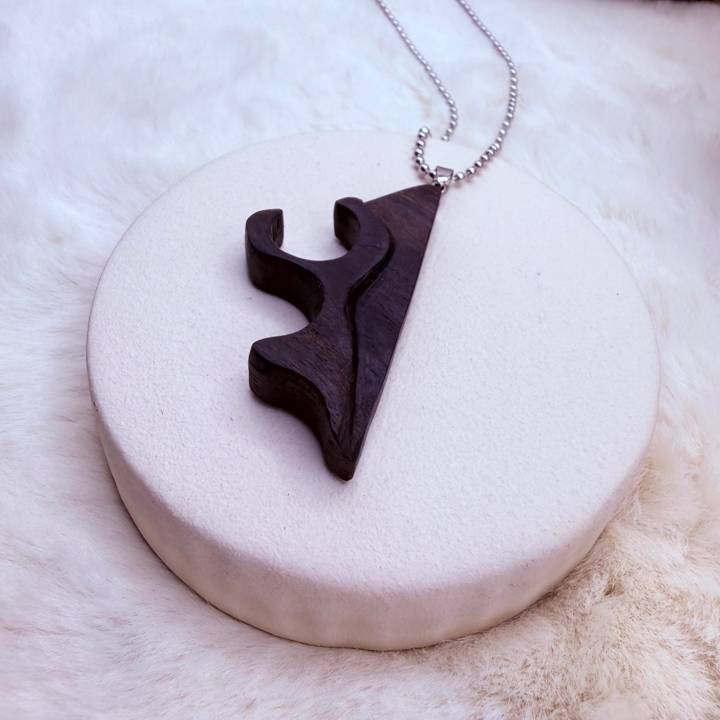 Black pendant necklace on a white stone surface