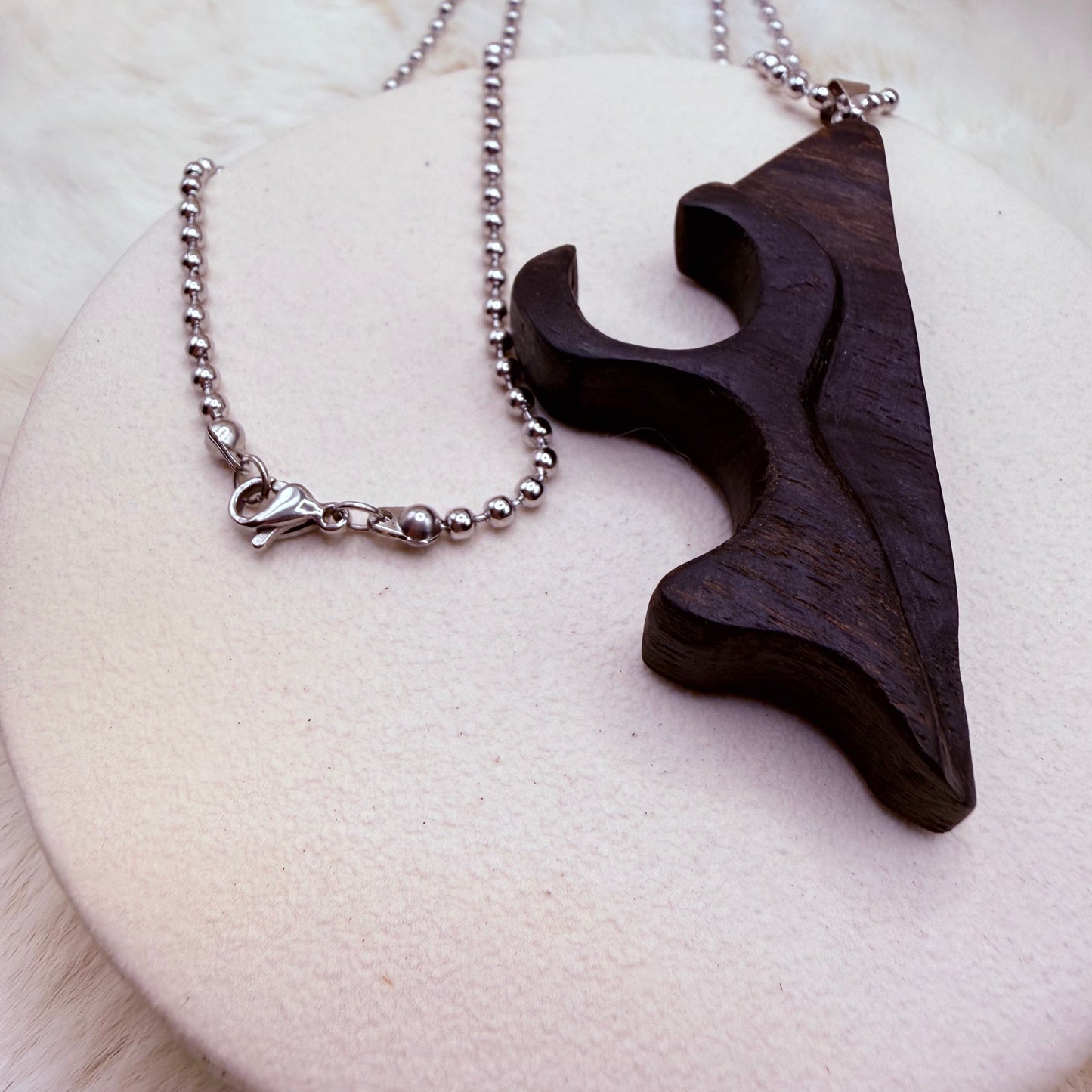 Wooden pendant on a silver chain against a white background