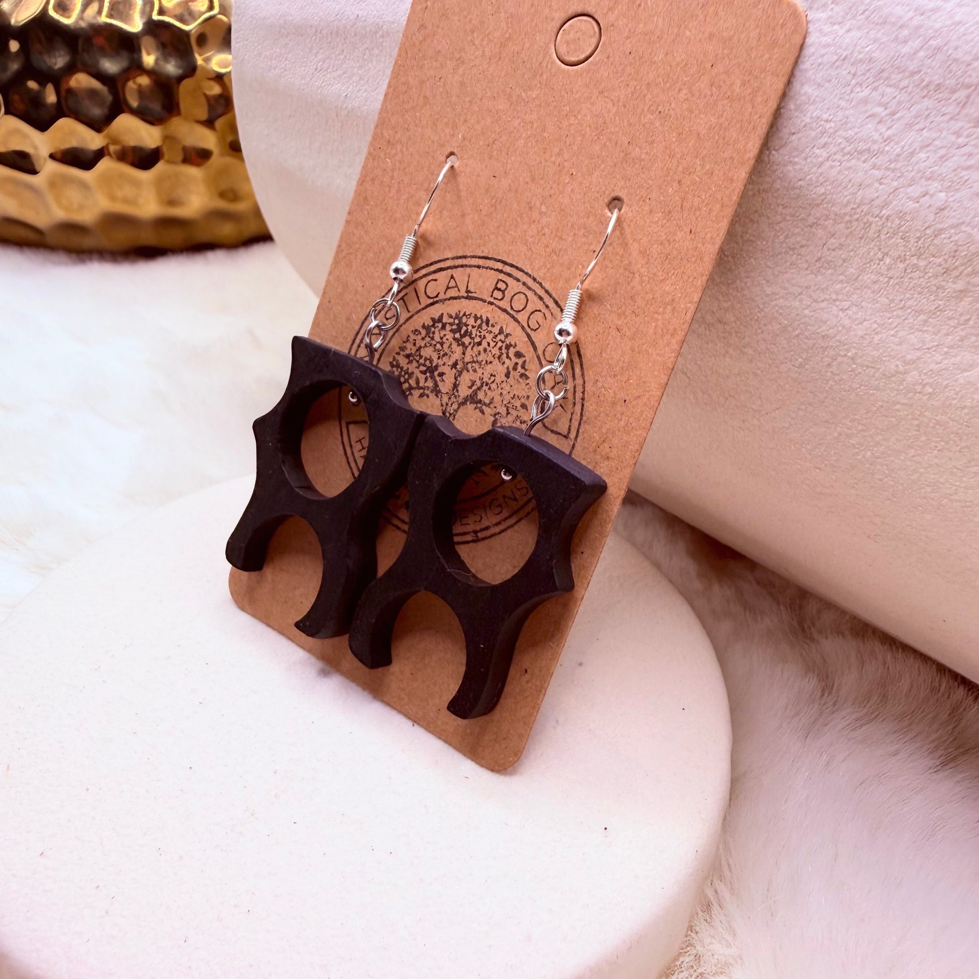 Organic shape Bog Oak earrings displayed on a neutral textured surface