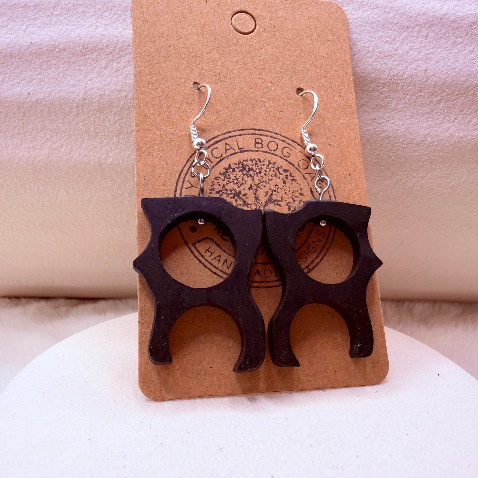 Handmade Irish Bog Oak earrings with organic cutout shape on a stone background