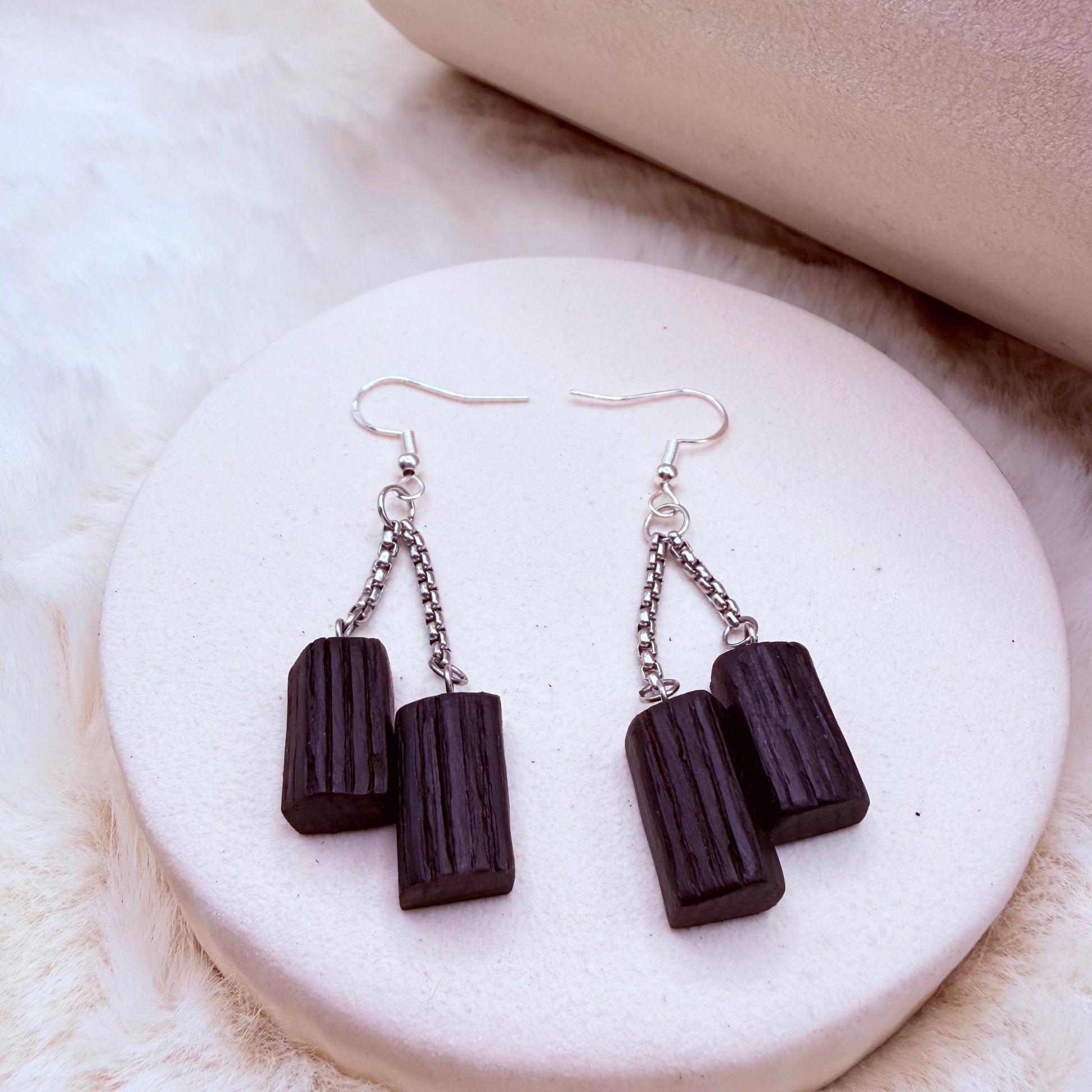 Handmade bog oak dangle earrings with stainless steel hooks on light background