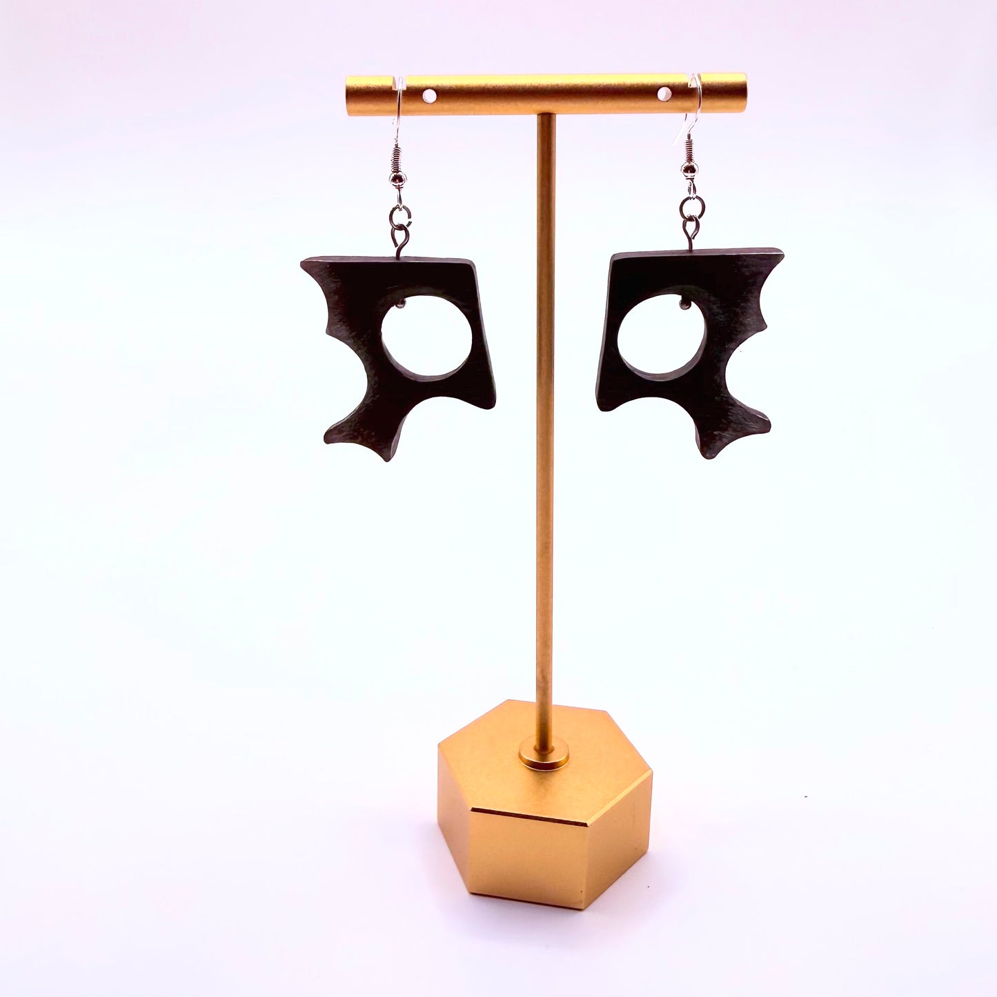 Black earrings on a gold stand against a white background