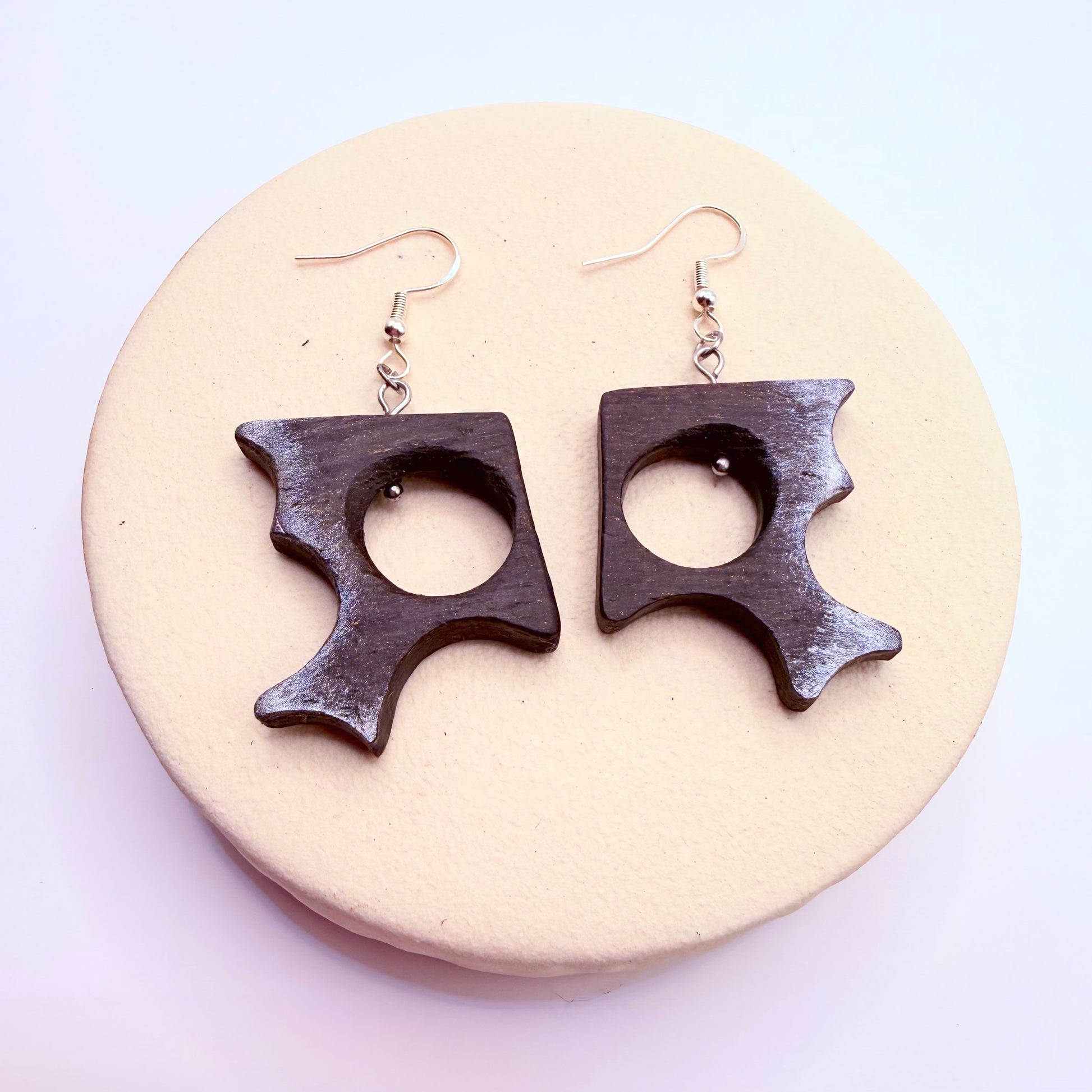 Sculptural bog oak earrings with geometric cutout on neutral background